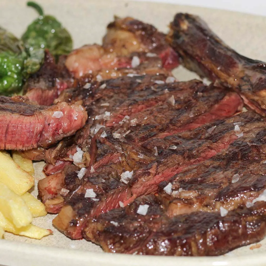 Sliced dry-aged ribeye with Padrón peppers and fries — The Beefeater Fuengirola